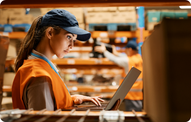 Woman in warehouse looking at laptop